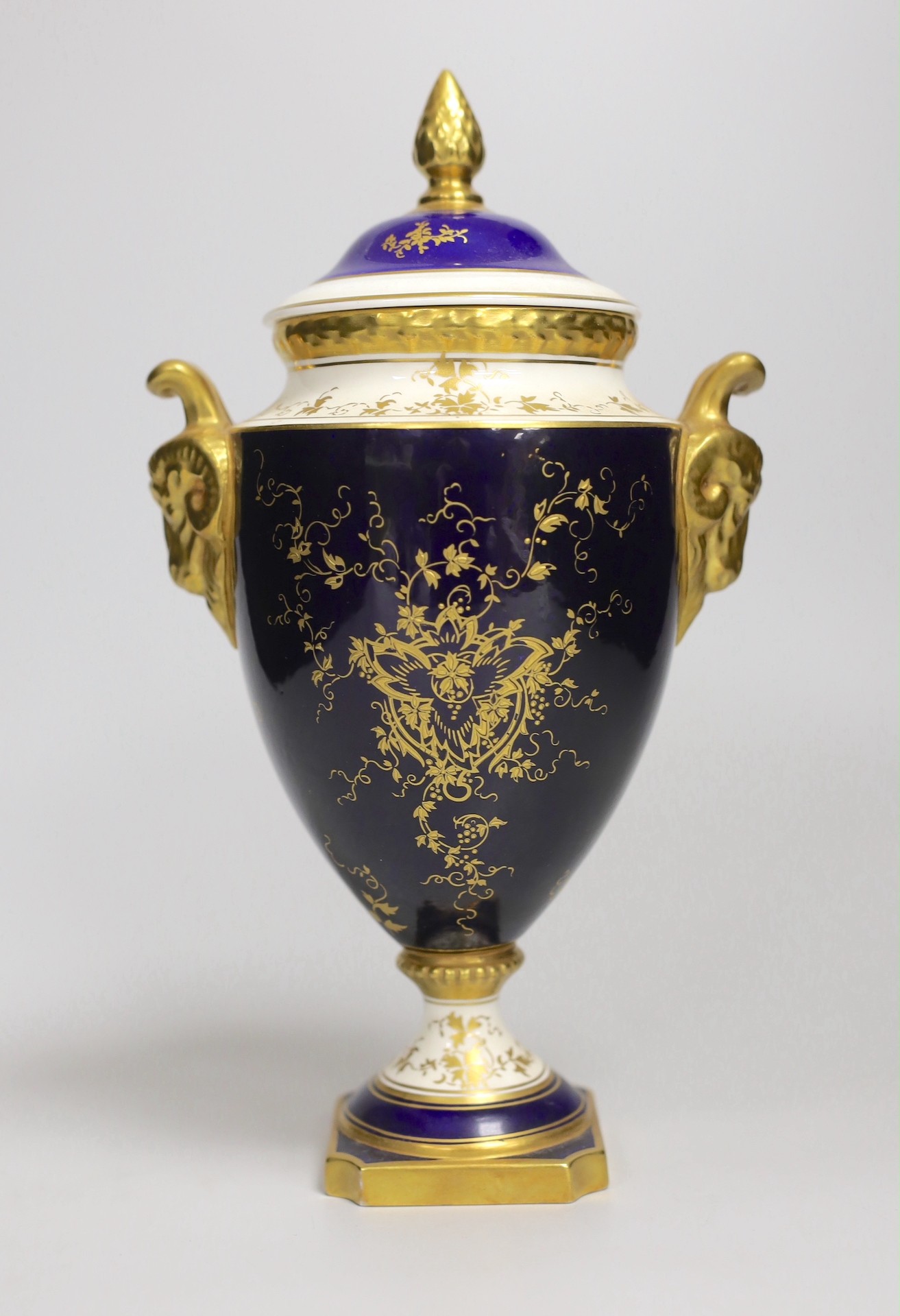 A Coalport urn and cover decorated with a floral reserve on a blue ground, 24cm